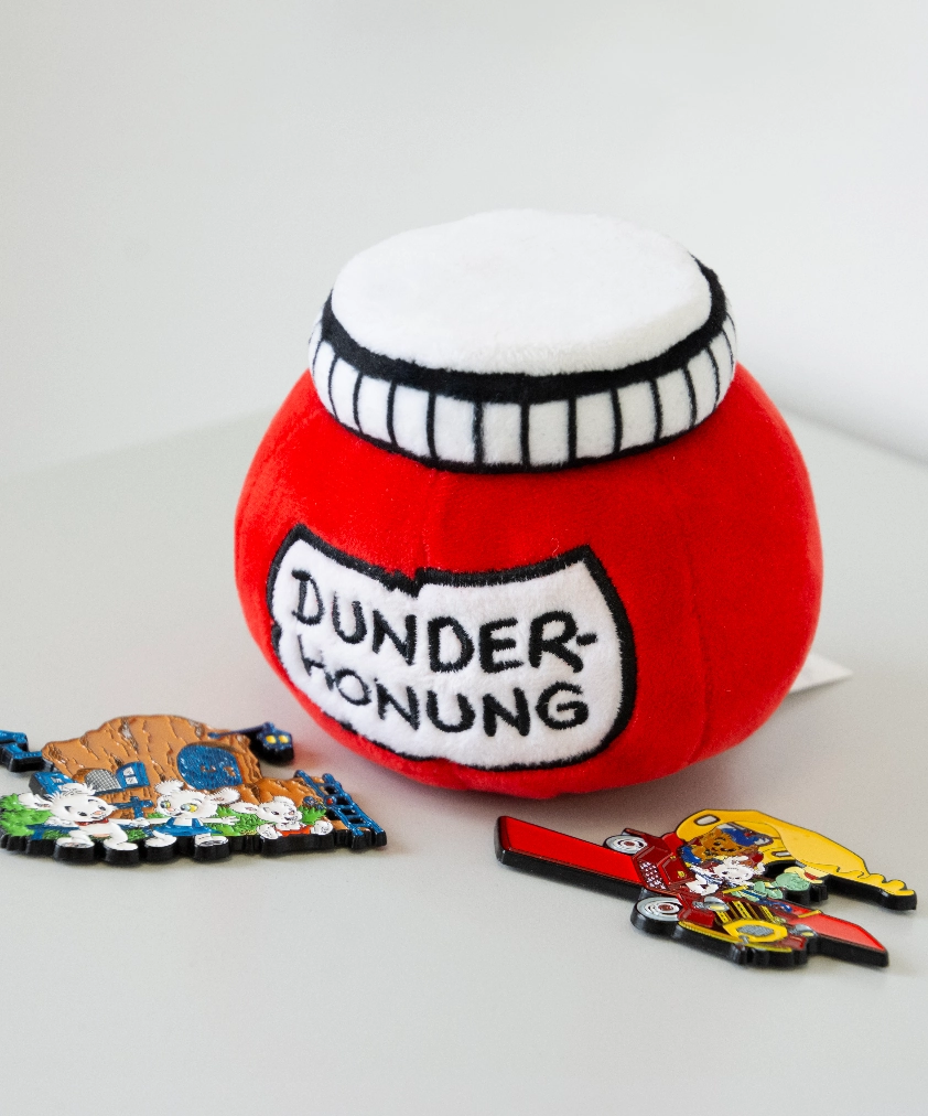 En n&auml;rbild p&aring; F&auml;rjestad BK merchandise: ett beigef&auml;rgat tyg med broderat klubbm&auml;rke och "KARLSTAD", ett golfklubbsfodral och en mugg